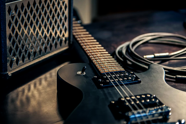 Guitarra deitada ao lado da caixa de som, para explicar se ela é igual ao violão
