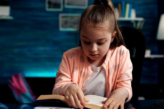 Menina com um livro sobre a mesa, aprendendo outro idioma